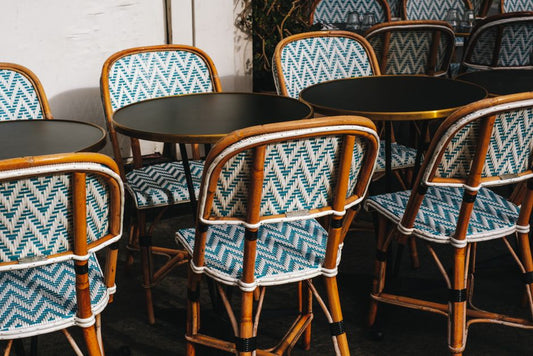 Stylish rattan chairs and tables in a sunlit outdoor café setting.